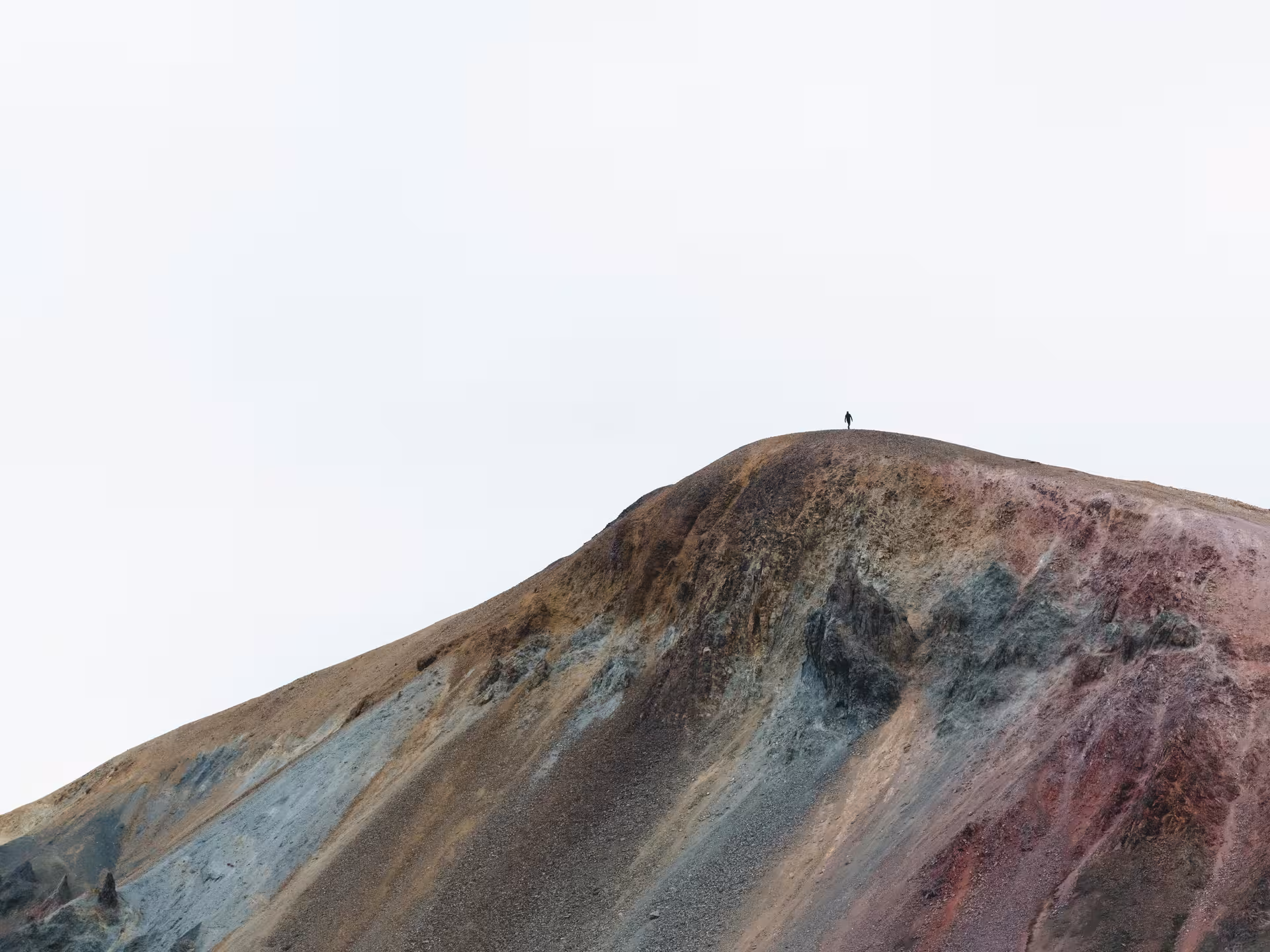 Lone hiker standing on colorful volcanic mountain peak on Reykjanes Peninsula, Iceland