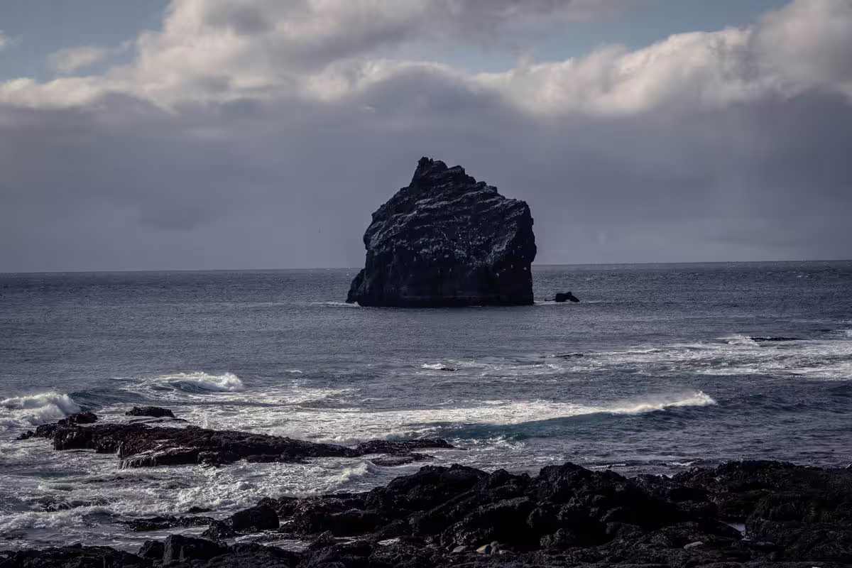 Dark volcanic sea stack rising from rough Atlantic Ocean waves on the Reykjanes Peninsula, Iceland