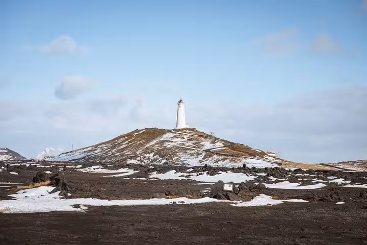 White lighthouse atop a snow-dusted volcanic hill on the Reykjanes Peninsula, Iceland