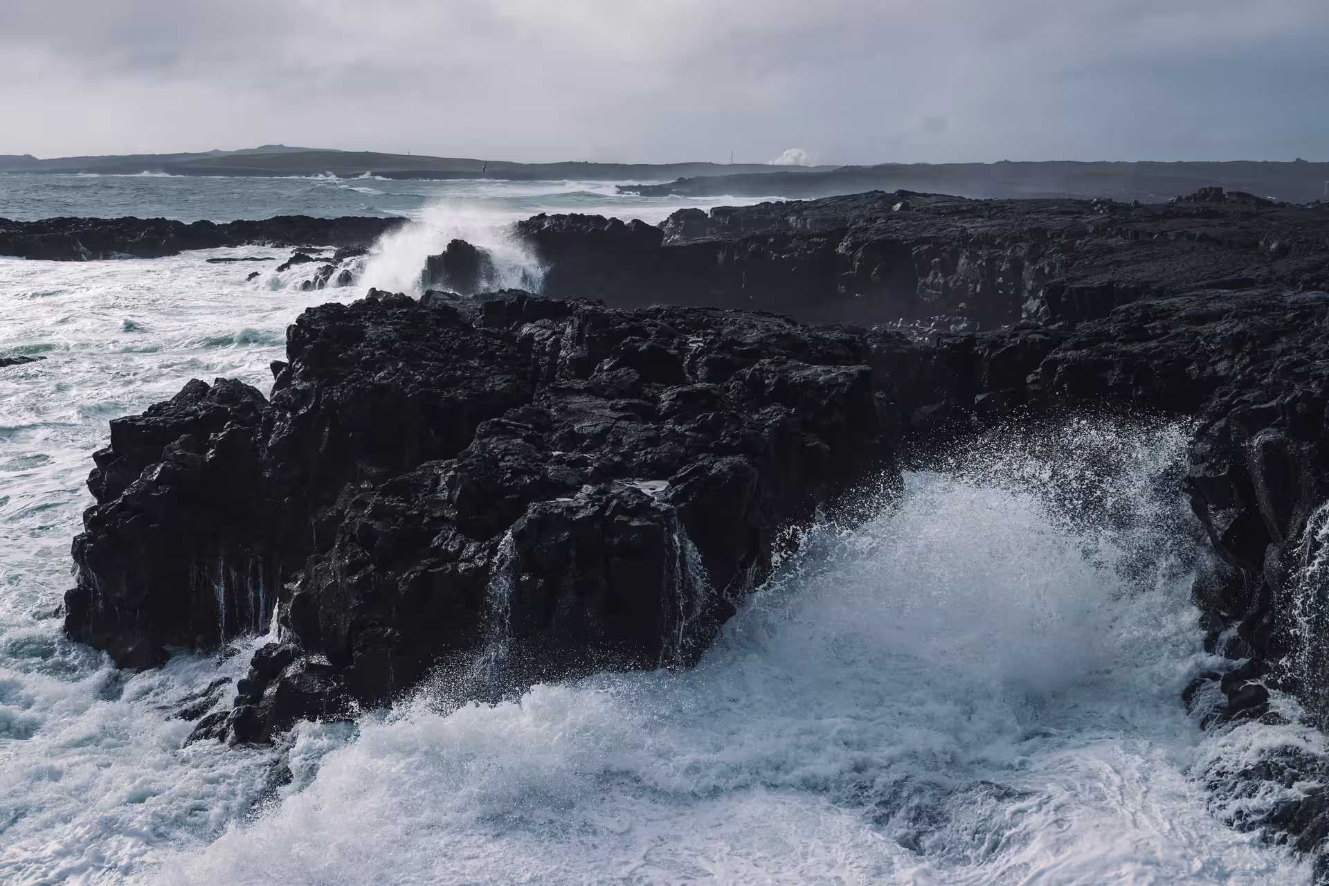 Powerful waves crashing against black volcanic rocks on the stormy Reykjanes coast, Iceland