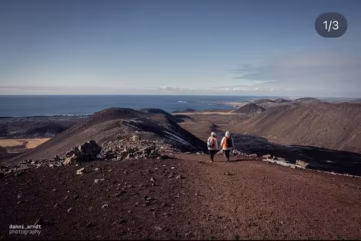 Two hikers walking along volcanic ridge on Reykjanes Peninsula with ocean views in Iceland