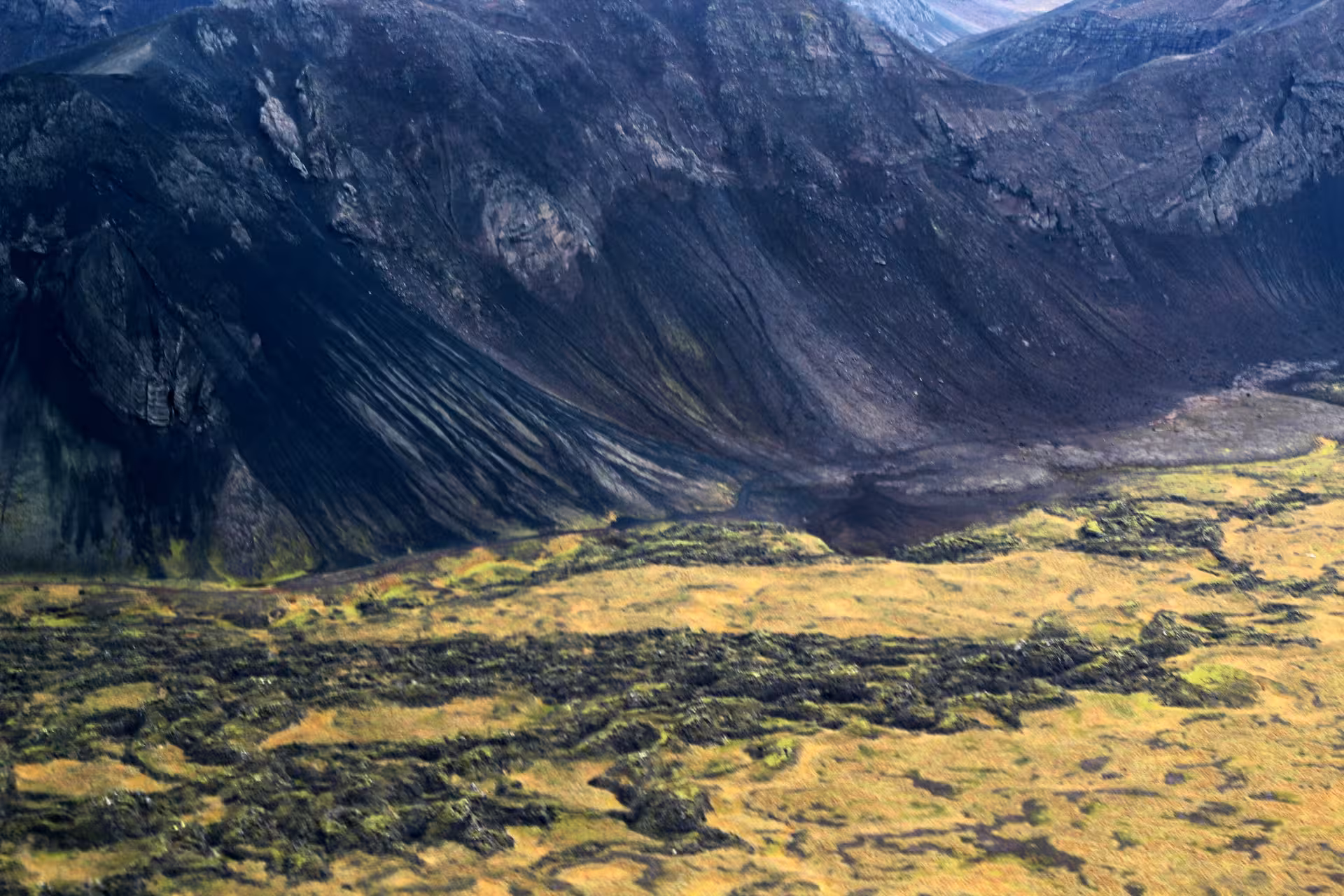 Aerial view of volcanic crater with dark lava slopes and green moss-covered lava fields in Reykjanes Iceland