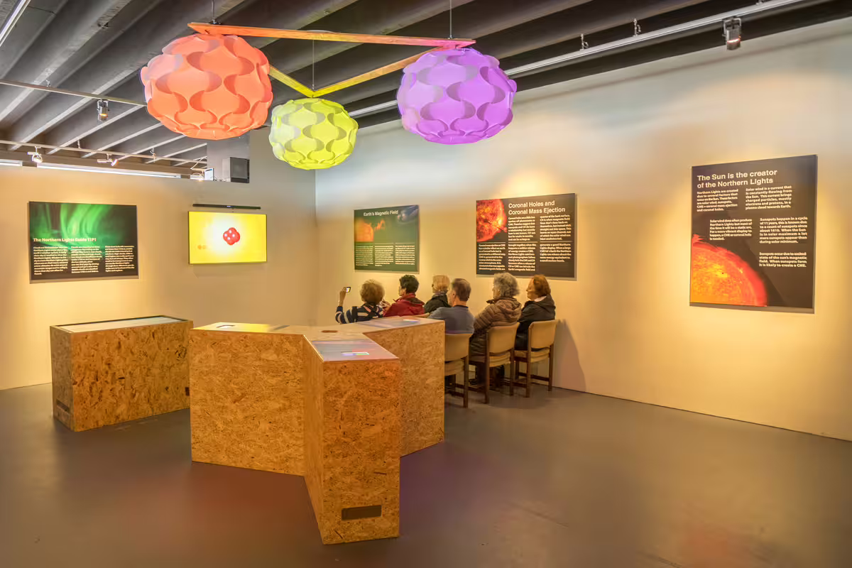 Aurora exhibition hall with northern lights displays, interactive panels, and colorful hanging lights in Reykjavik