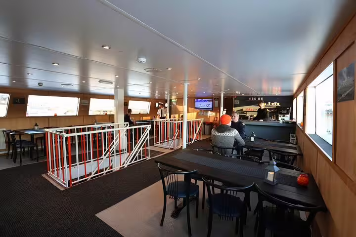 Indoor seating area on a boat tour vessel in Reykjavik with tables, chairs, and a bar counter