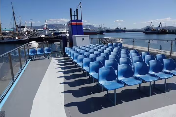 Blue outdoor seating on boat deck with Reykjavik harbor and vessels in background