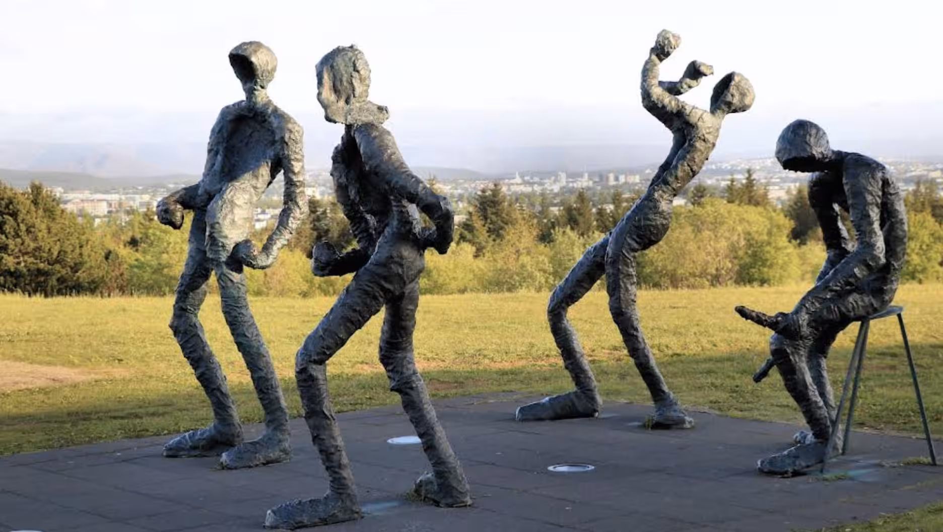 Four abstract bronze sculptures of human figures in dynamic poses outdoors in Reykjavik, Iceland