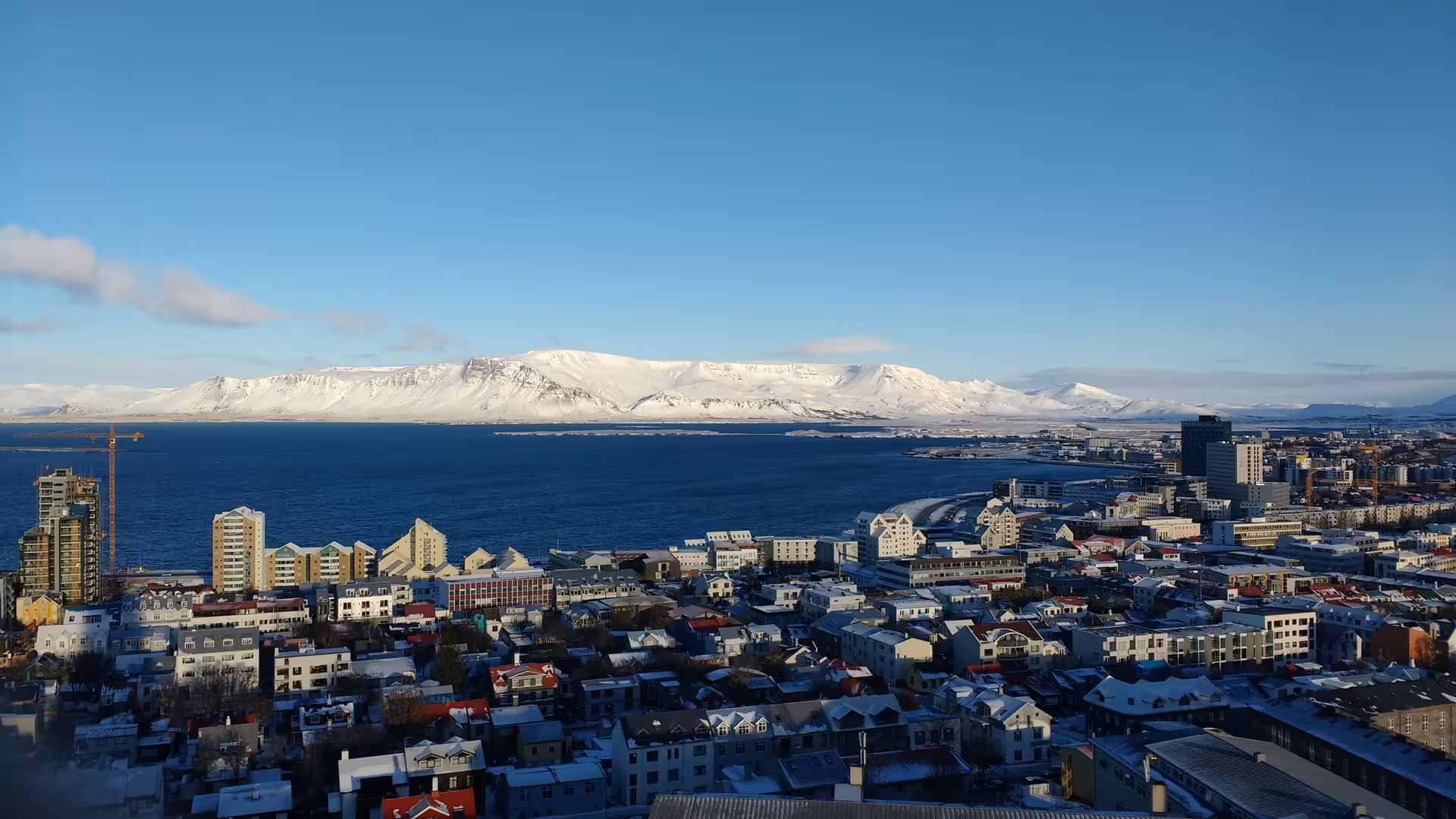 Aerial view of Reykjavik city with snow-capped mountains and bay in winter