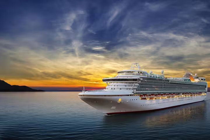 Large cruise ship sailing at sunset on calm ocean waters near mountainous coastline