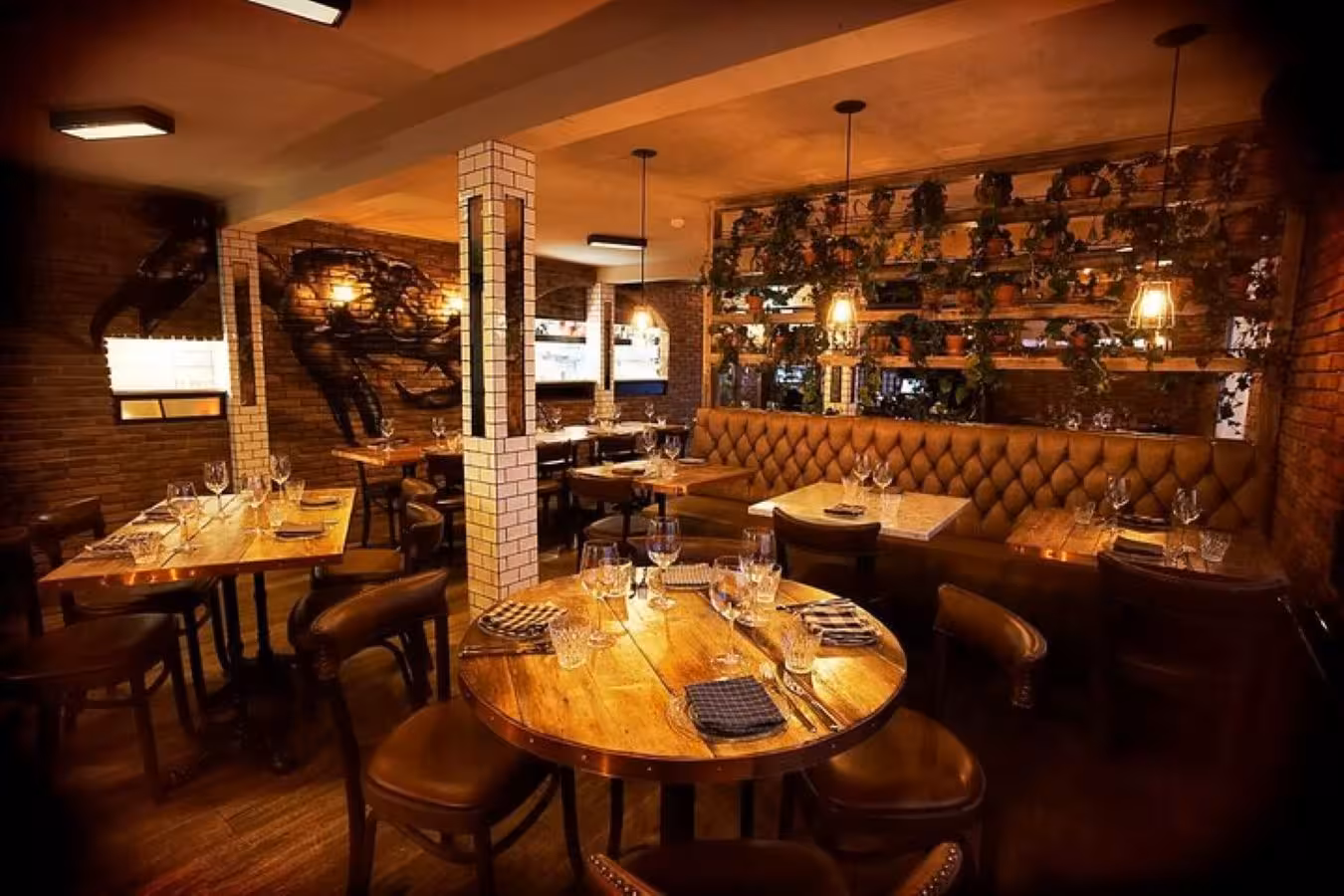 Warm rustic restaurant interior with wooden tables, leather banquettes, and lush plant wall for Reykjavik dinner