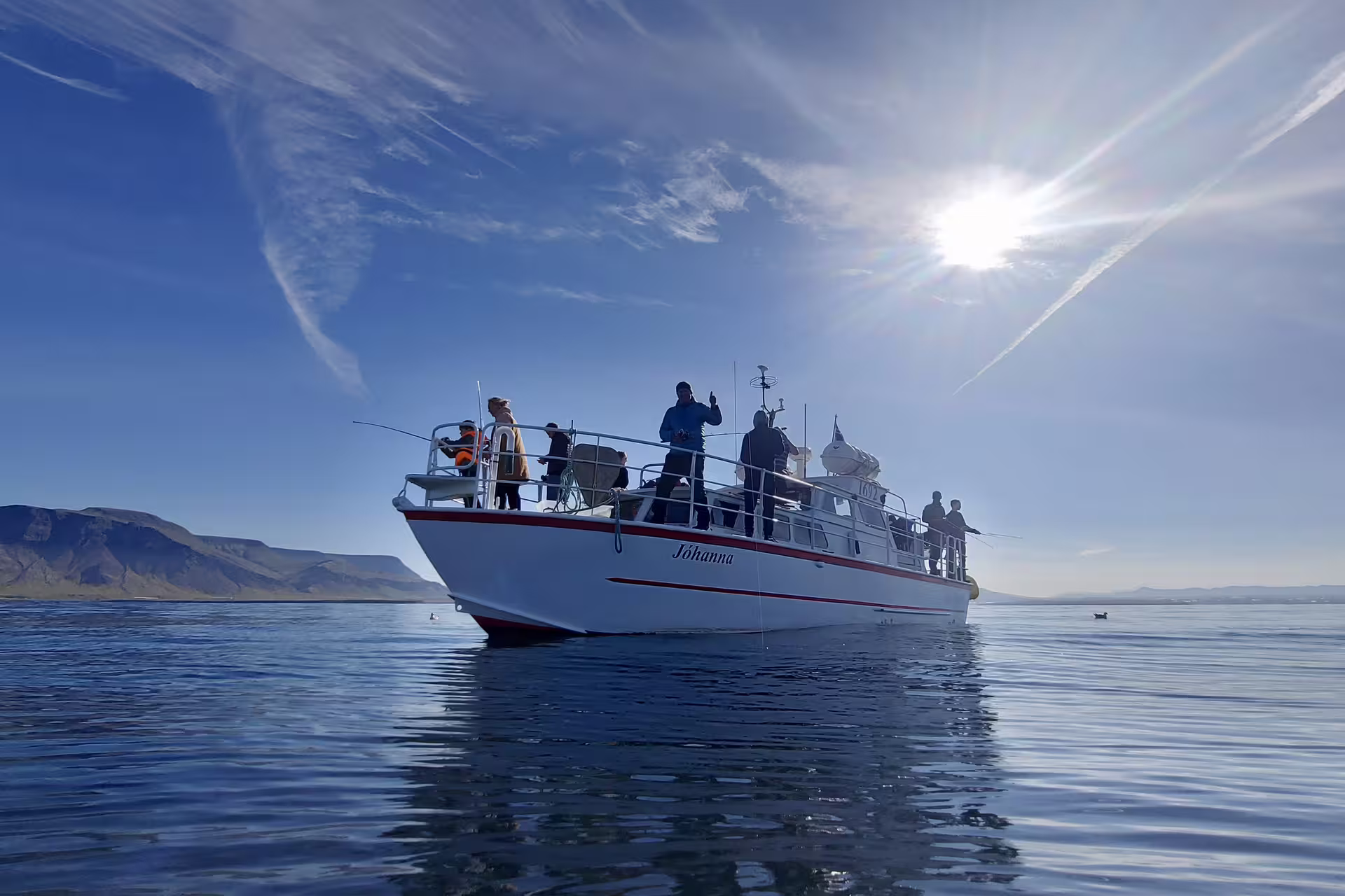 Fishing boat Jóhanna with passengers on calm Reykjavik waters, mountains in background under sunny blue sky