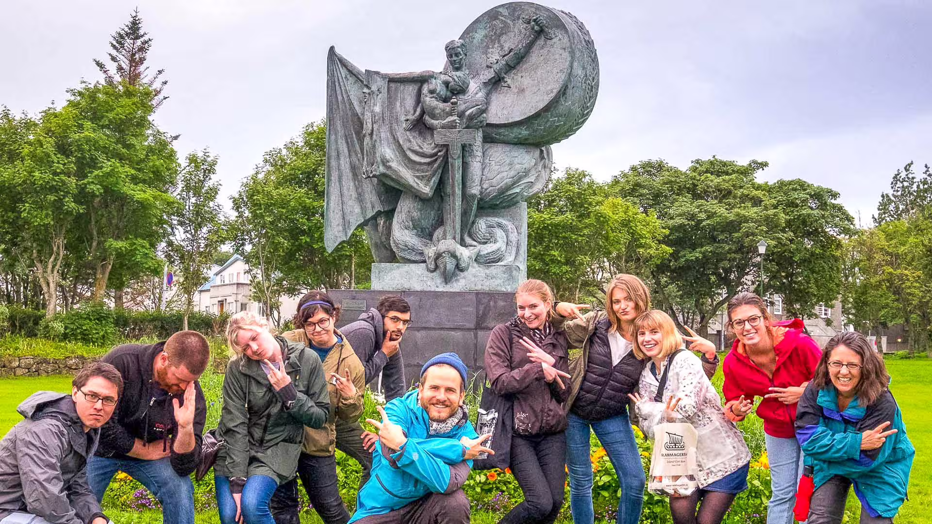 Tour group posing playfully in front of a Viking bronze statue in Reykjavik park