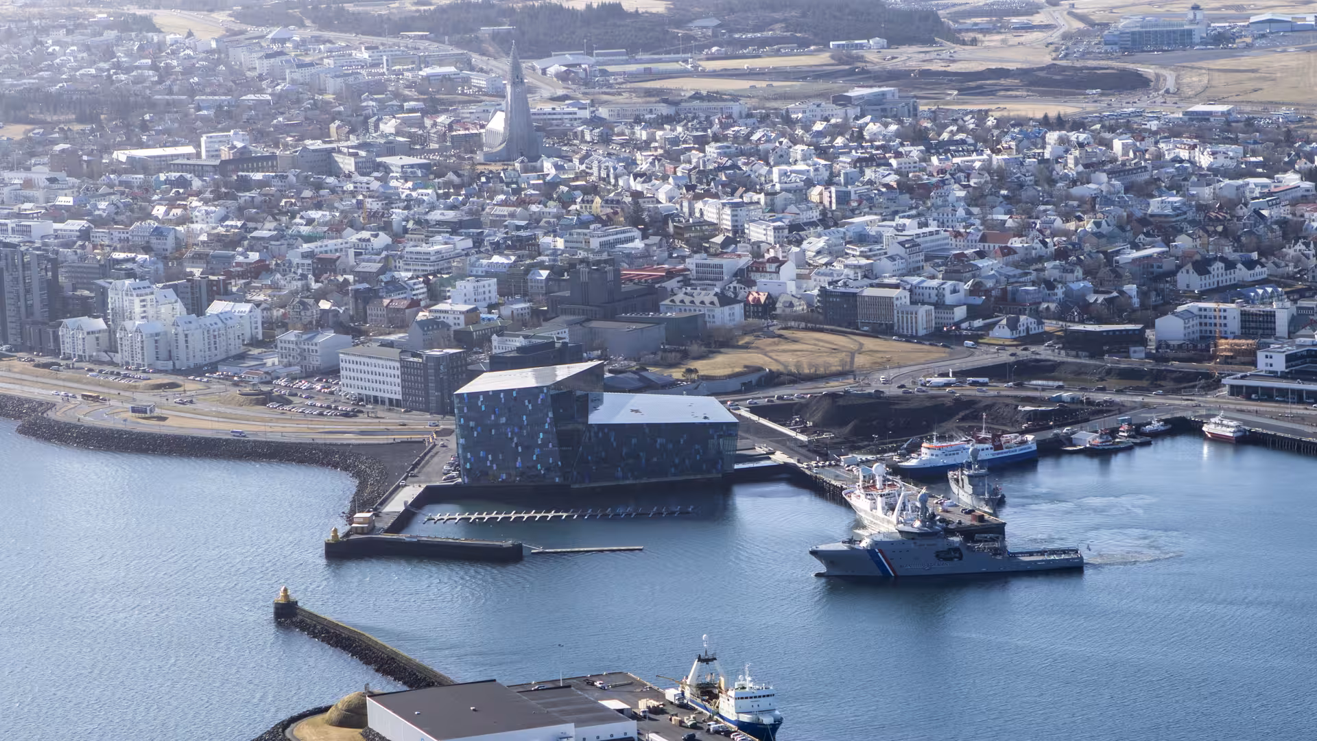 Aerial view of Reykjavik harbor with Harpa Concert Hall and city skyline from airplane tour