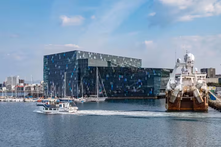 Harpa Concert Hall waterfront in Reykjavik harbor with boats and blue geometric glass facade