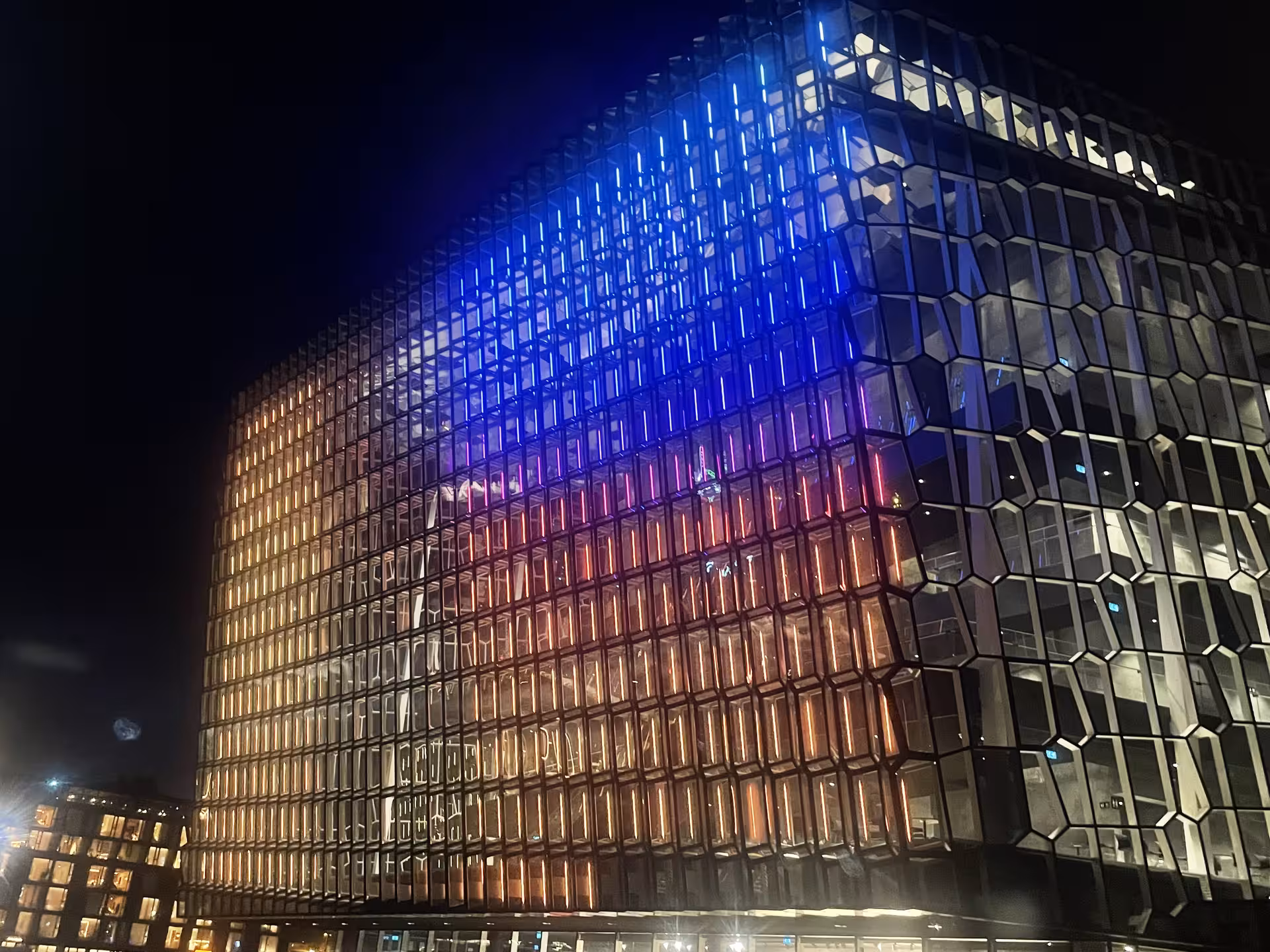 Harpa Concert Hall illuminated with colorful lights at night in Reykjavik, Iceland