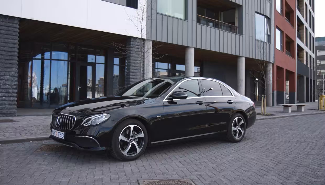 Black Mercedes-Benz E-Class sedan parked outside modern building in Reykjavik for airport transfer