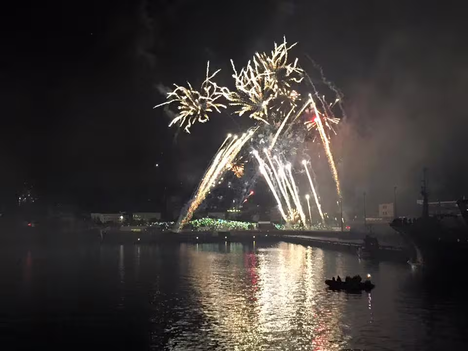 Colorful New Year's Eve fireworks exploding over Reykjavik harbor at night with boat in foreground