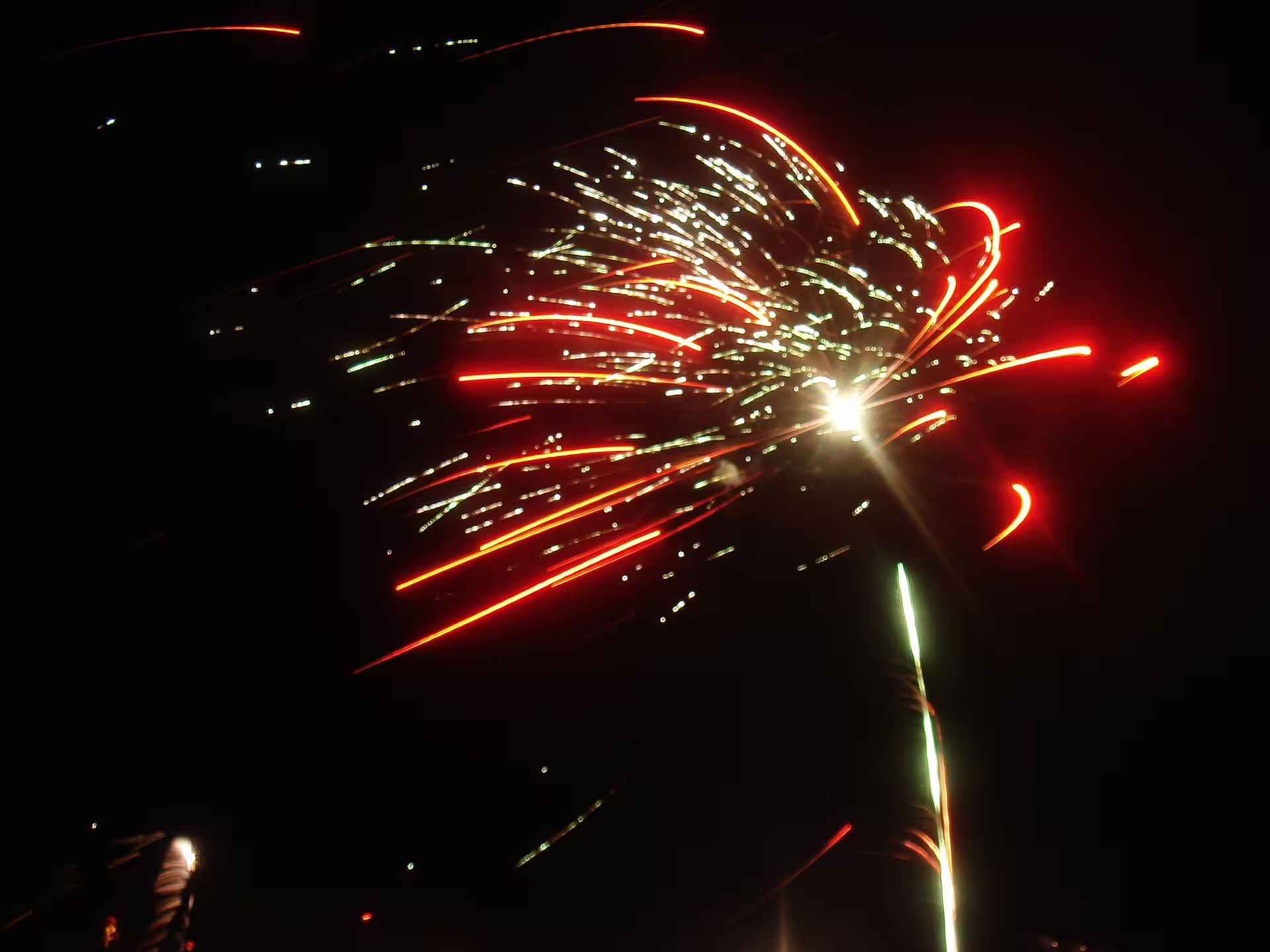 Red and white fireworks bursting against dark night sky over Reykjavik New Year's Eve celebration