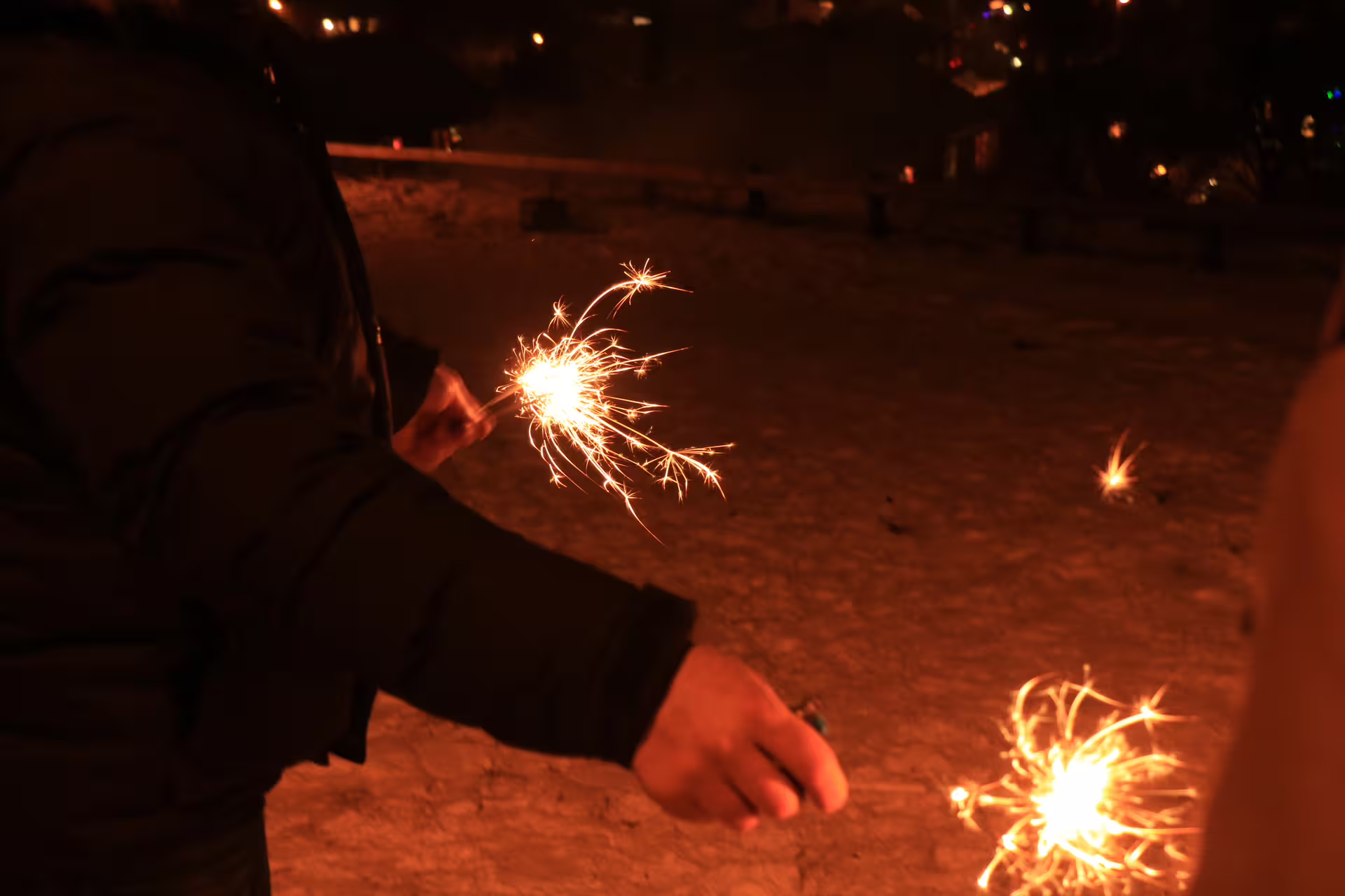 Person holding sparklers at night during New Year's Eve celebrations in Reykjavik
