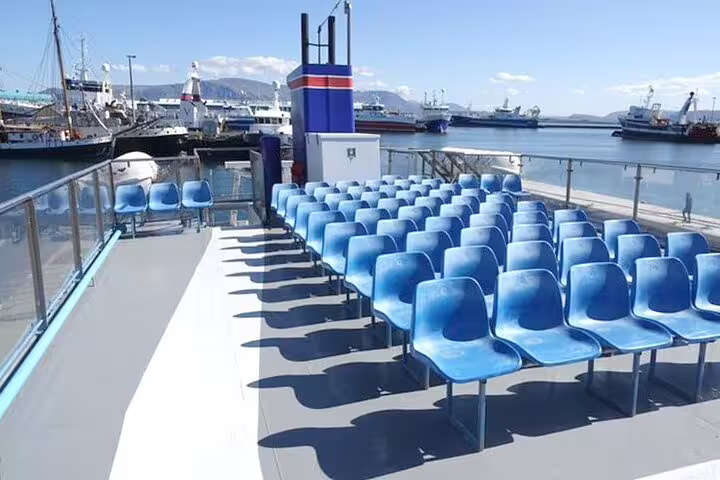 Blue outdoor seating deck on a Reykjavik tour boat with harbor and ships in background