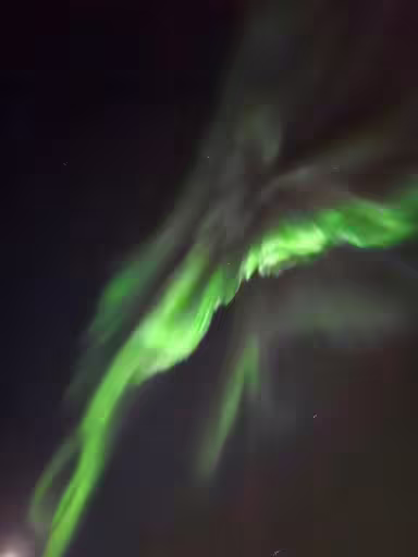 Vivid green northern lights aurora borealis swirling across dark night sky in Reykjavik Iceland