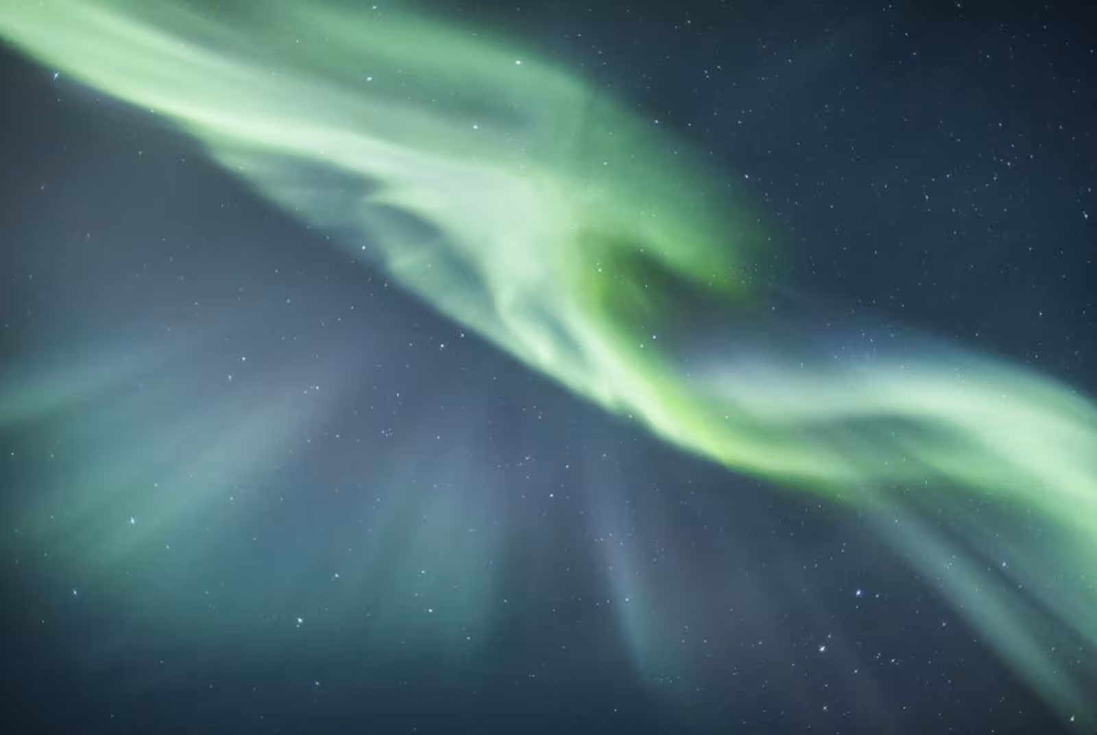 Vivid green northern lights swirling across a starry night sky in Reykjavik, Iceland