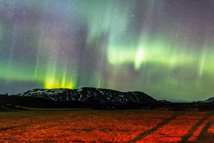 Vivid green northern lights dancing over snow-capped mountains near Reykjavik on a starry night
