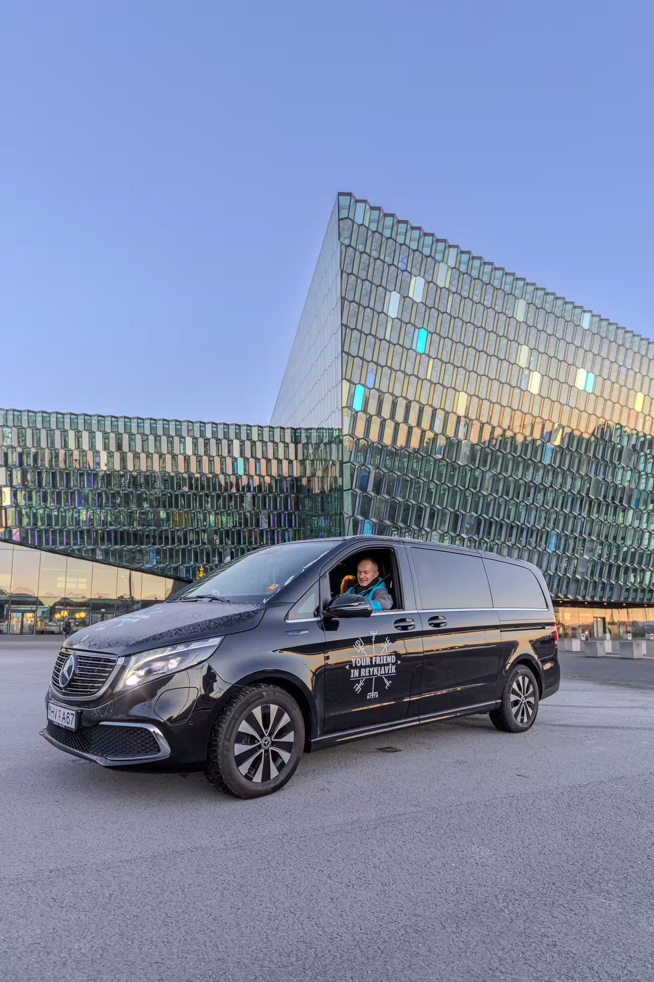 A tour vehicle being driven by a Guide from Your Friend in Reykjavik in front of the Harpa Concert Hall in Reykjavik