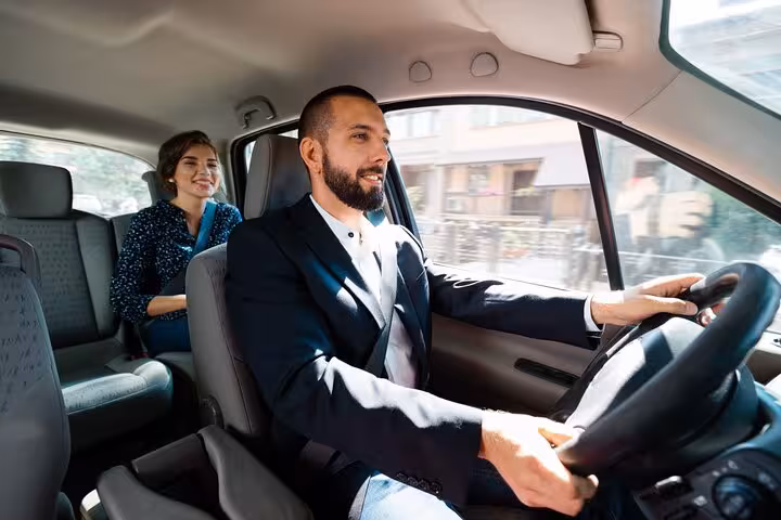 Professional driver in suit driving passengers from Keflavik Airport to Reykjavik in private transfer vehicle