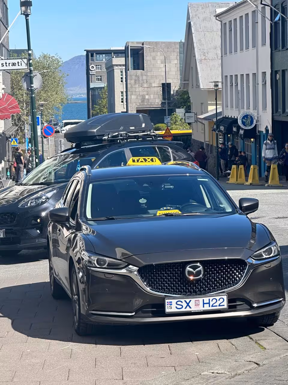 Black Mazda taxi on Reykjavik street with yellow taxi sign, Icelandic license plate SX H22