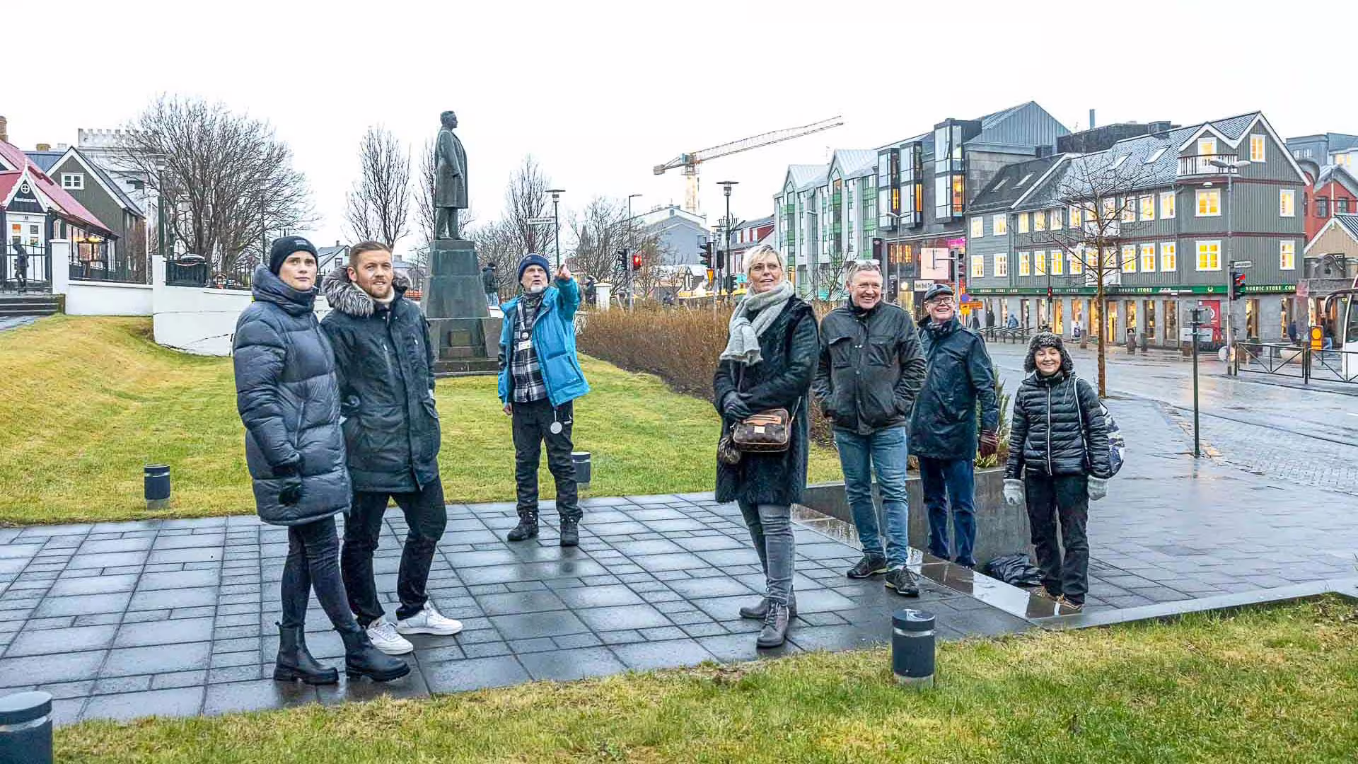 Tour guide pointing out city landmarks to a group of tourists in Reykjavik city center during winter