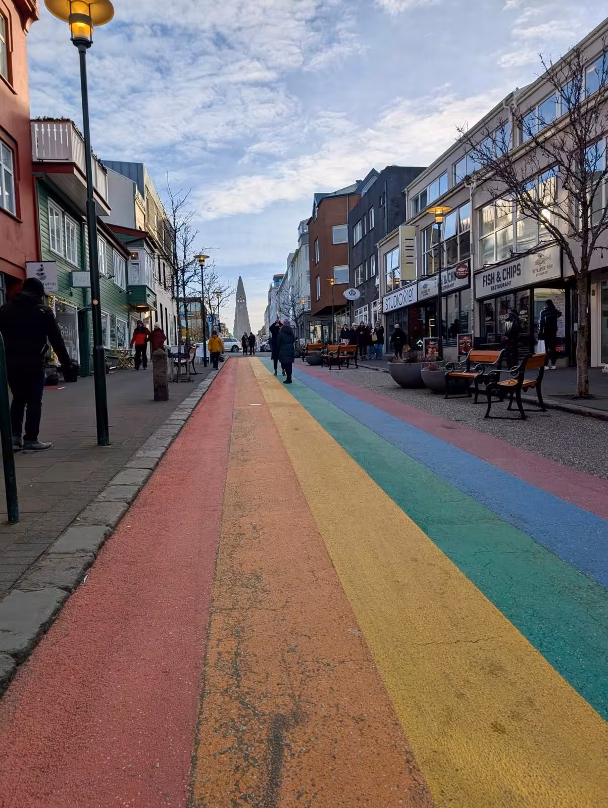 Rainbow street in Reykjavik with Hallgrímskirkja church tower visible in the background, Iceland