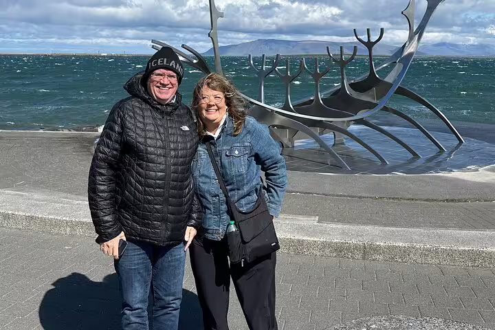 Couple smiling at Sun Voyager sculpture by Reykjavik waterfront on Iceland transfer tour