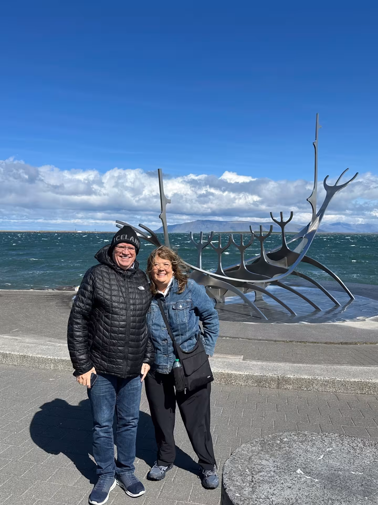 Couple smiling at Sun Voyager sculpture on Reykjavik waterfront in Iceland on a sunny day