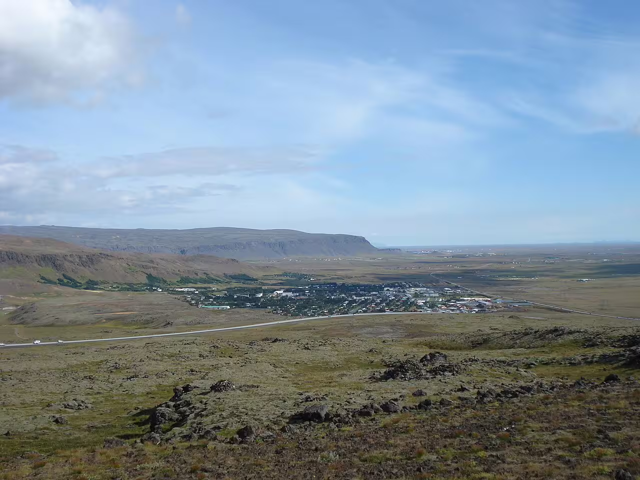 Aerial view of Reykjavik town nestled in volcanic lava fields with flat-topped mountains in background