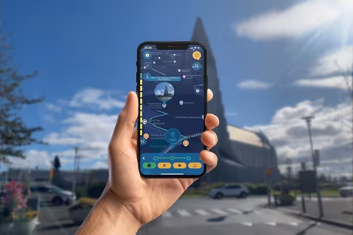 Hand holding smartphone with Viking walking tour app in front of Hallgrímskirkja church in Reykjavik