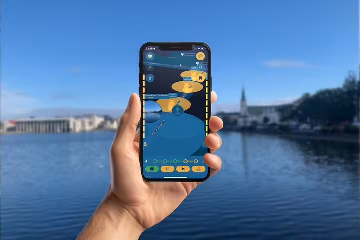 Hand holding smartphone displaying Viking walking tour app with duck icons over Reykjavik waterfront