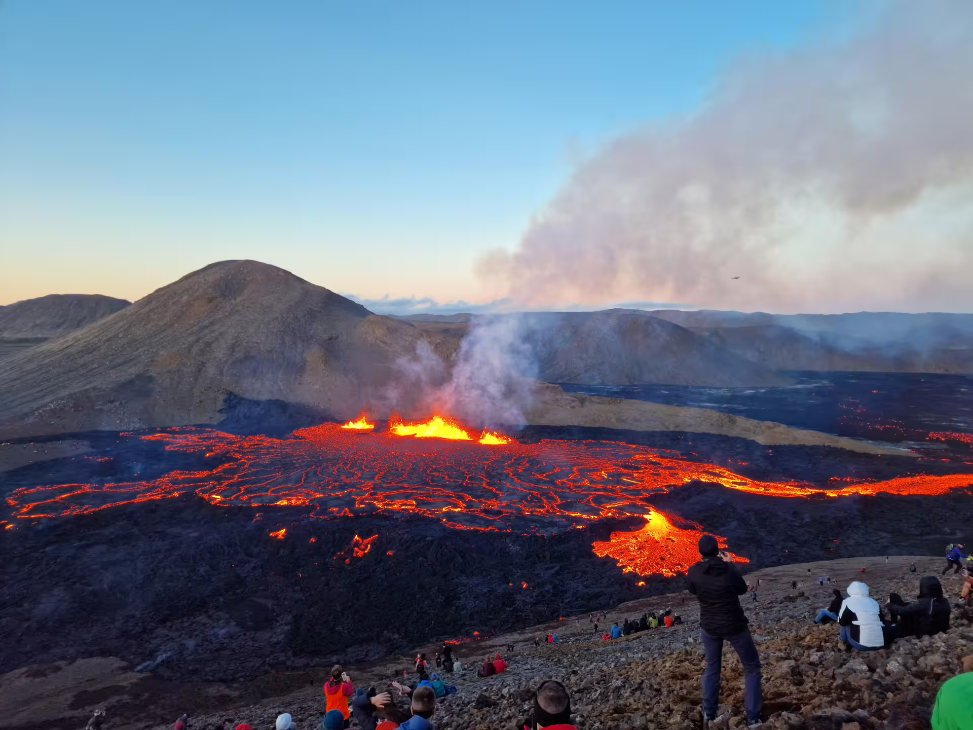 Tourists watching glowing lava fields and erupting volcanic vents on a Iceland volcano hike near Reykjavik