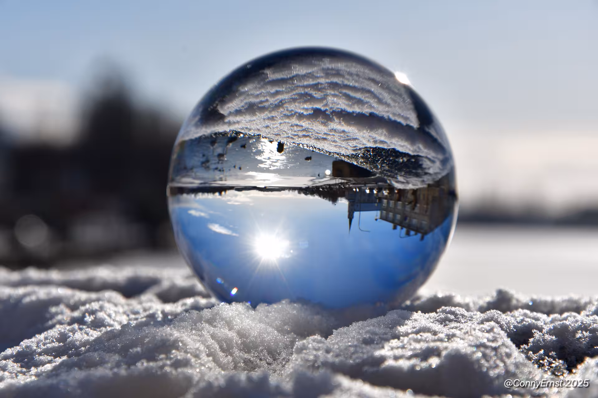 Crystal ball on snow reflecting Reykjavik landmarks and blue winter sky with sunburst