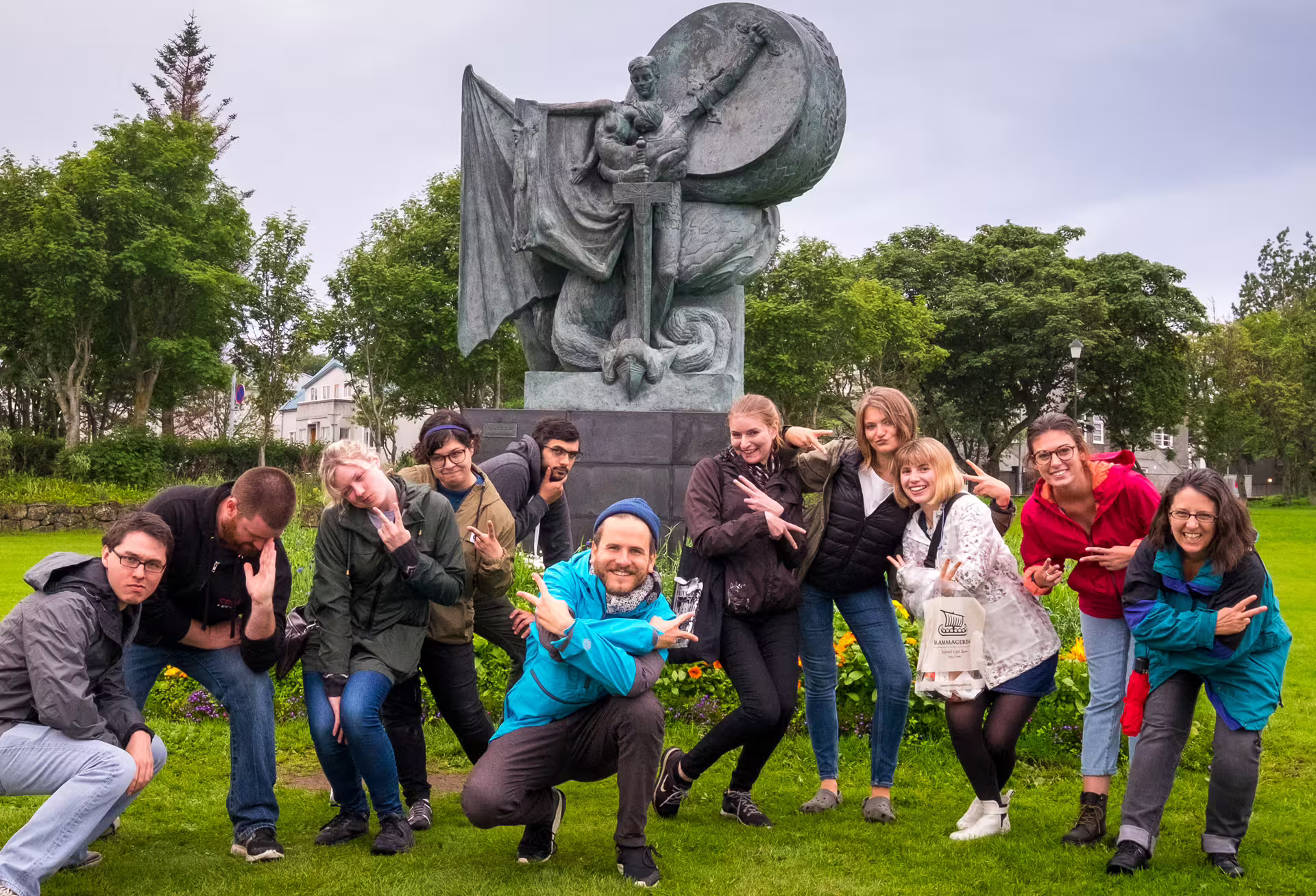 Tour group posing and laughing in front of a bronze Viking statue in Reykjavik park