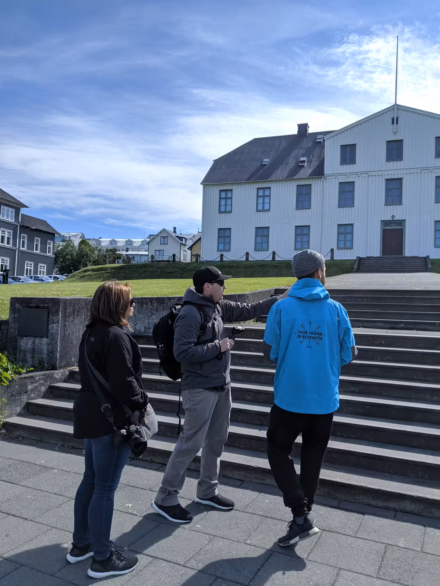 Tour guide in blue jacket pointing out landmarks to two tourists on a Reykjavik walking tour
