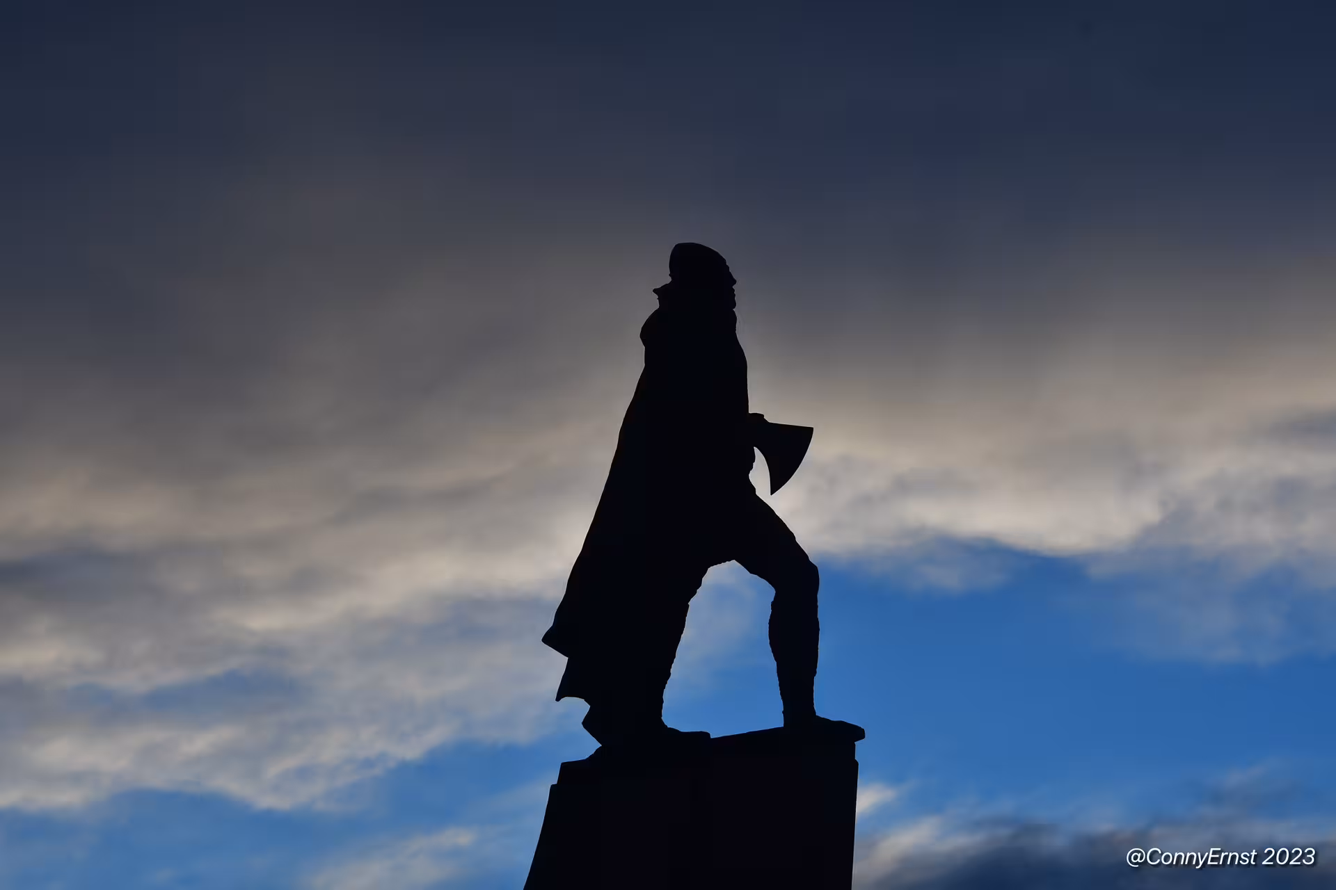 Silhouette of a historic statue against a dramatic blue sky in Reykjavik at dusk