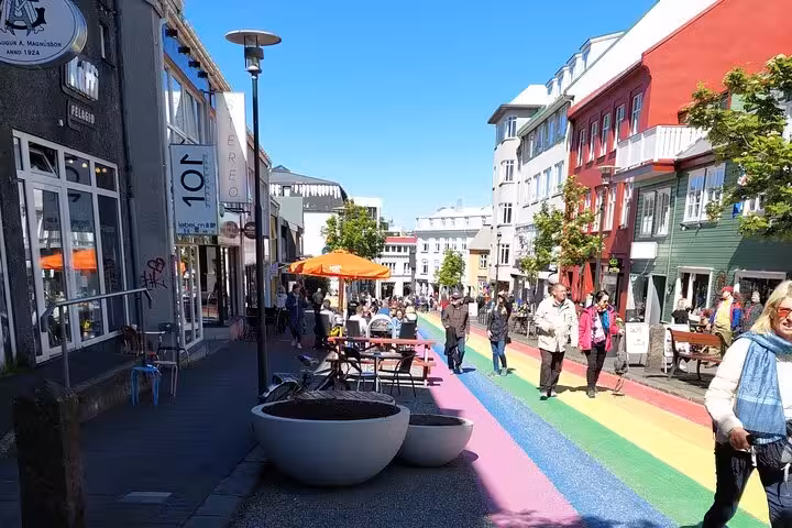 Rainbow street in downtown Reykjavik with colorful buildings and pedestrians on a sunny day