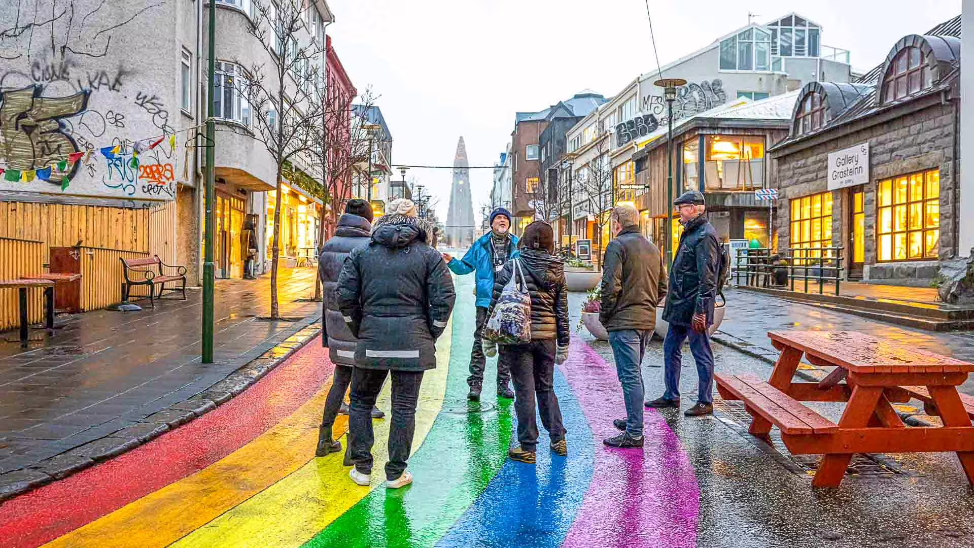 Group on rainbow-painted street in Reykjavik with Hallgrímskirkja church in background on rainy day