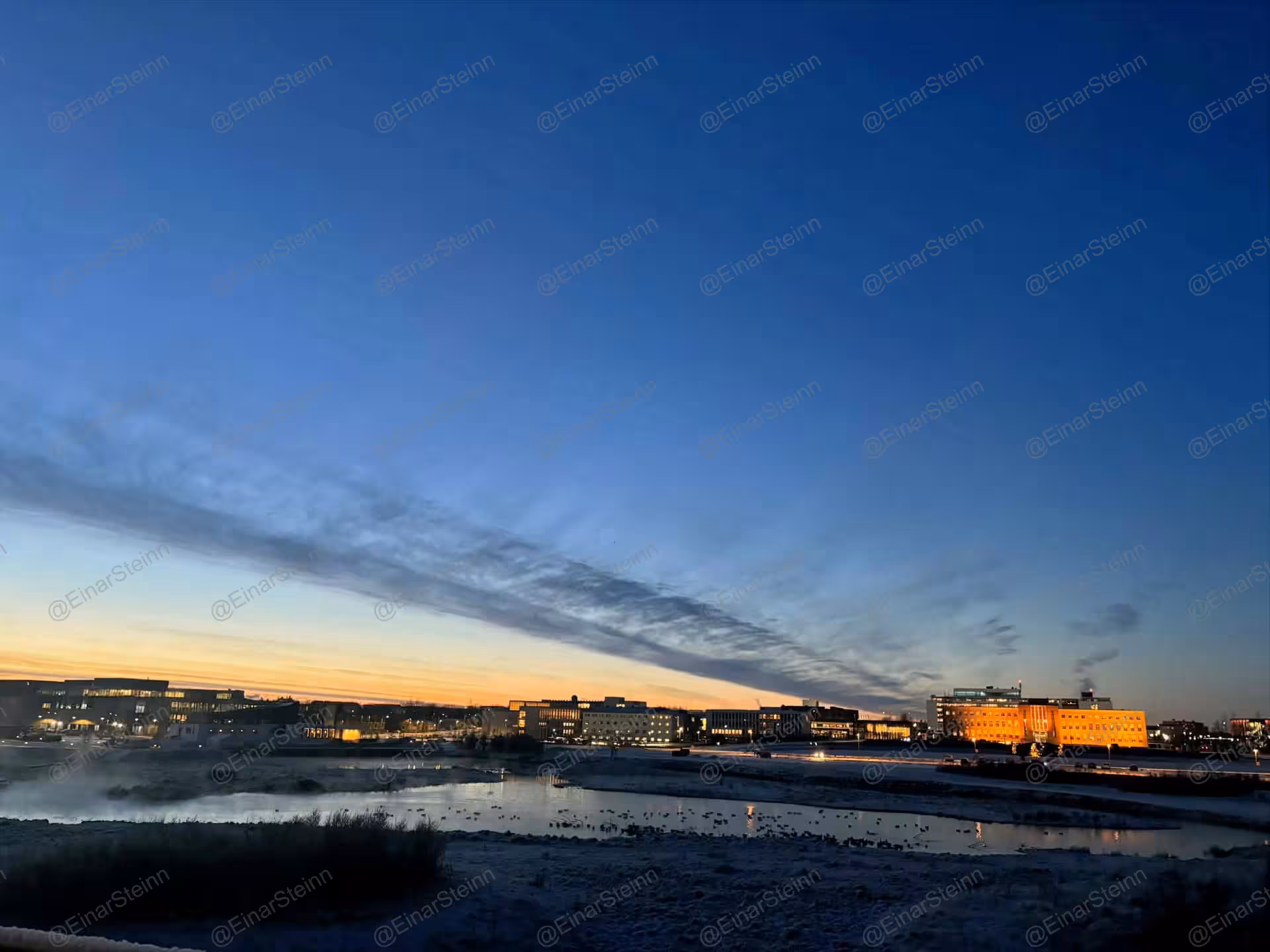 Reykjavik city skyline at twilight with glowing buildings reflected in a calm lake