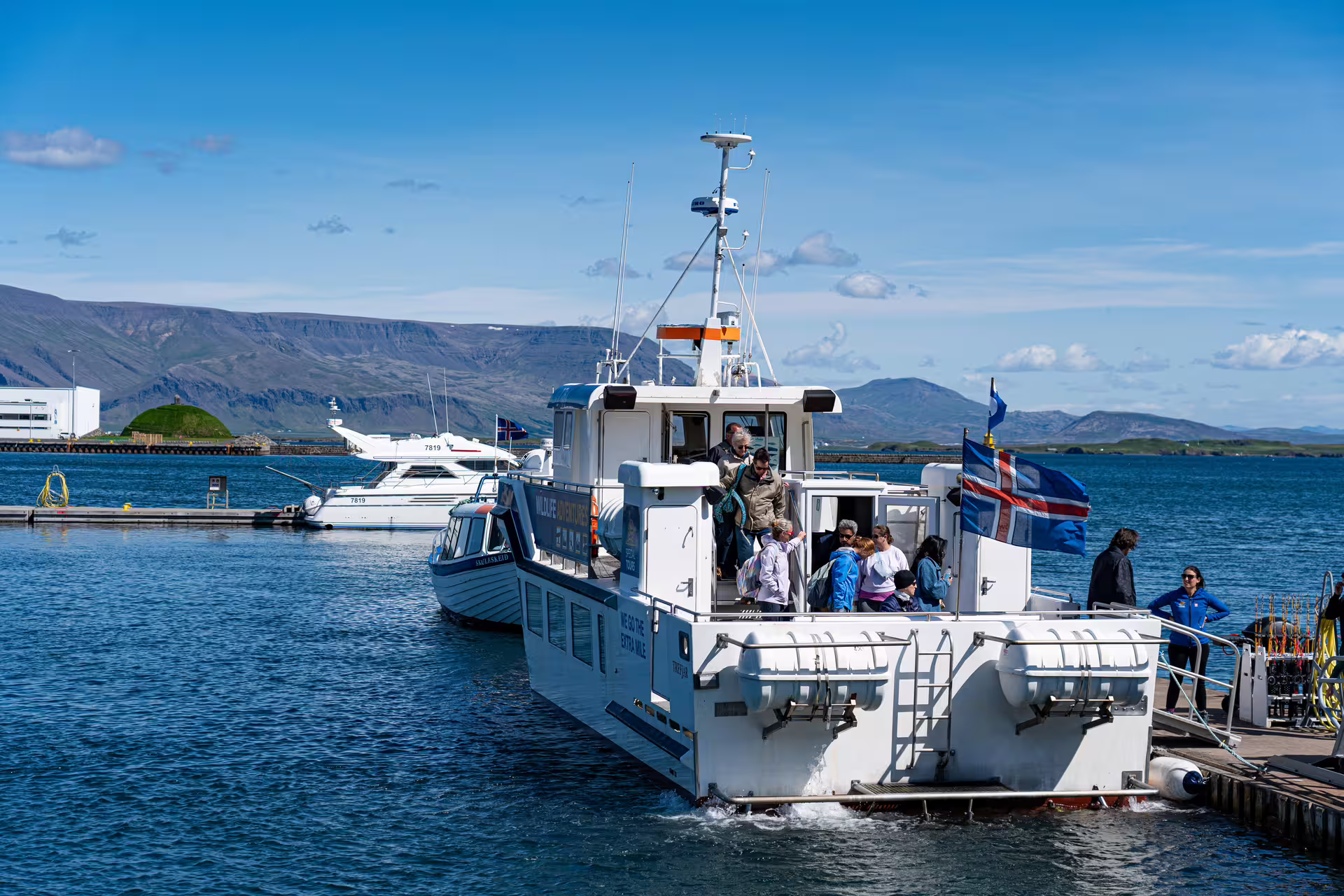 Whale watching tour boat docked at Reykjavik Old Harbour with passengers boarding, Iceland flag visible
