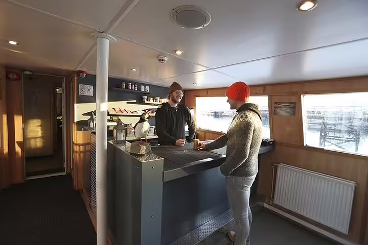 Staff serving a customer at the onboard café bar of a whale watching boat in Reykjavik harbor
