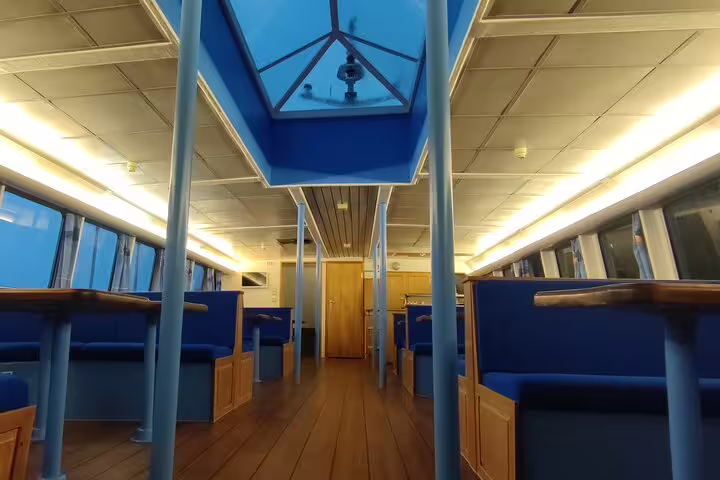 Interior passenger cabin of whale watching cruise boat with blue seats and wooden deck in Reykjavik