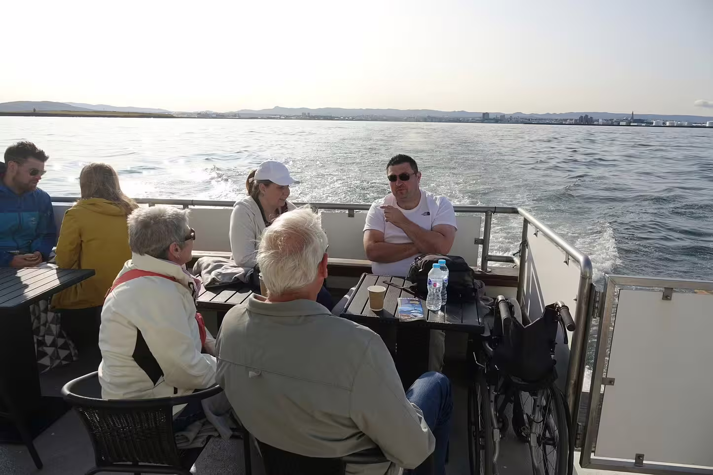 Tourists sitting on yacht deck during whale watching tour from Reykjavik with ocean views