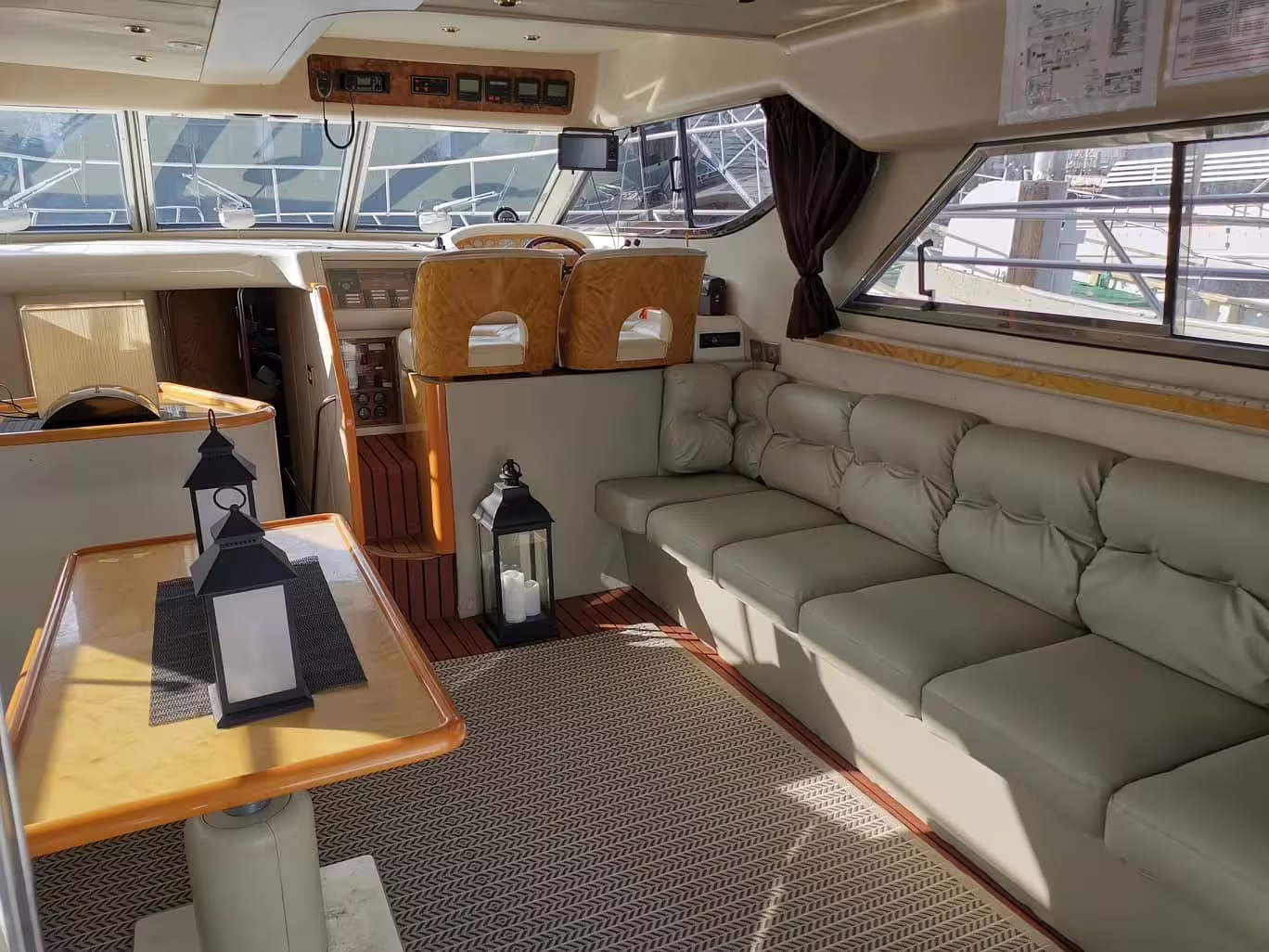 Luxury yacht salon with cream leather sofa, wooden dining table, and helm station for whale watching tour from Reykjavik