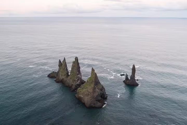 Aerial view of Reynisdrangar basalt sea stacks rising from the Atlantic Ocean on Iceland's south coast